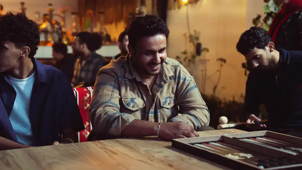 Friends laughing and playing a board game at a cozy cafe table